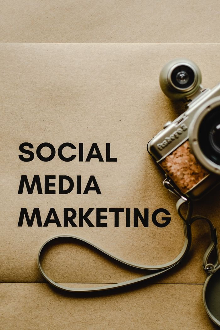 Mastering the First Impression: Your intriguing post title goes here Close-up of a vintage camera next to a social media marketing concept text on a brown background.